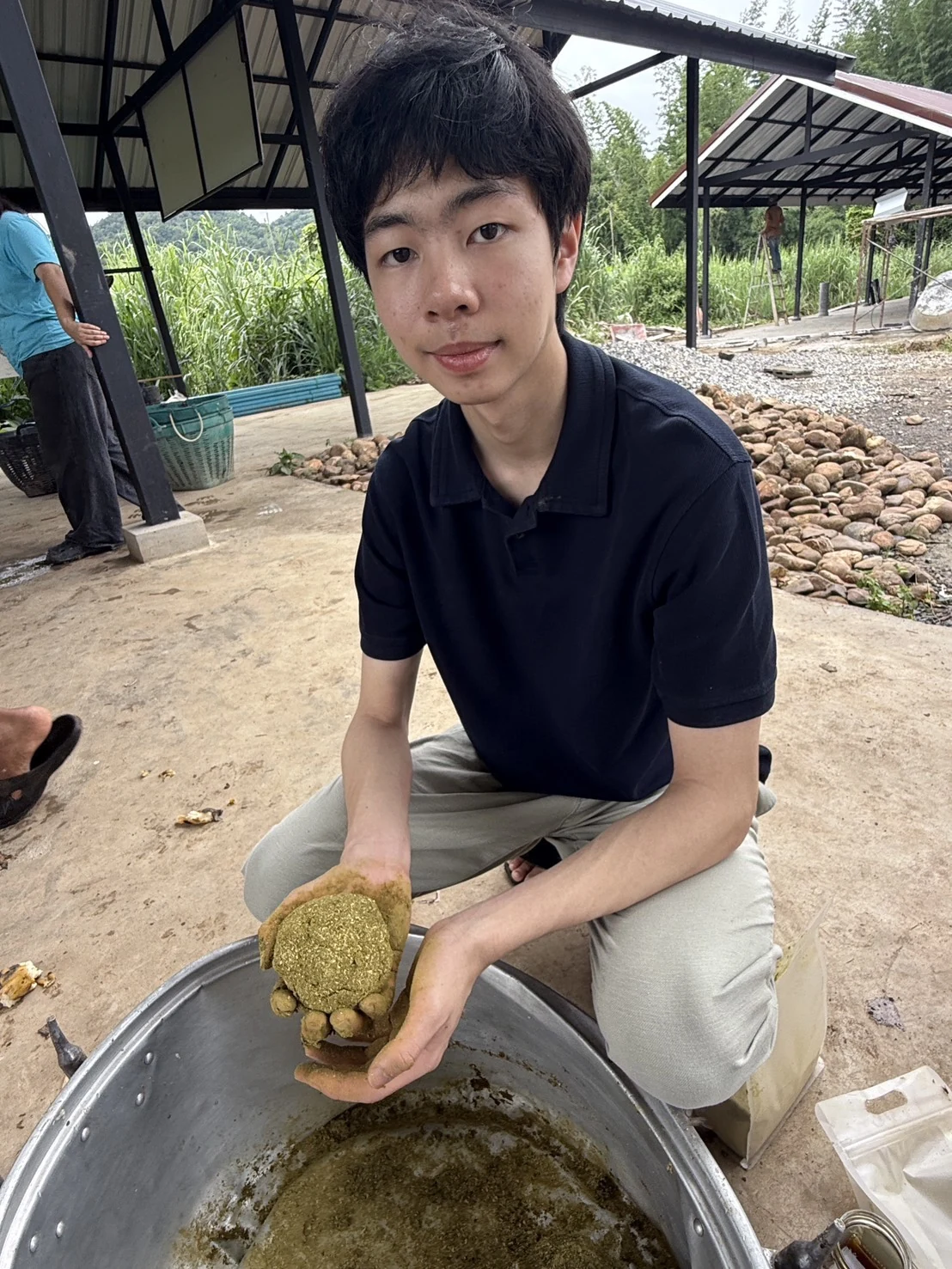 Holding a prepared supplement ball above the mixing bowl at Somboon